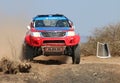 Front view close-up of red and blue Toyota Hilux single cab rally car at road crossing